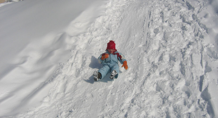Kind rutscht vom Schneehaufen